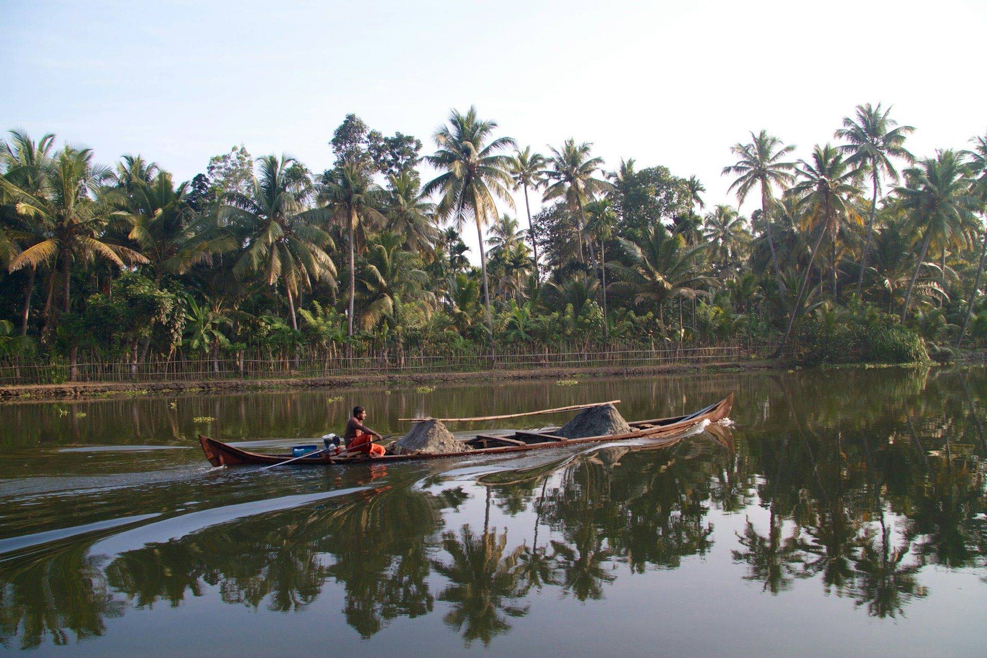 Kerala snake boat gliding through palm-lined backwaters at dusk
